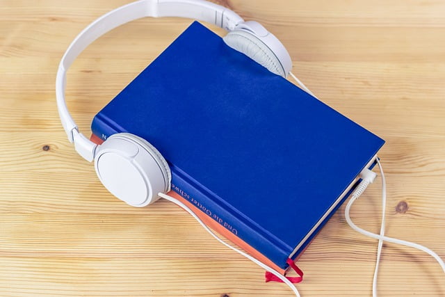 blue hardback book with white earphones on a light colored wood table, image used for audiobook post