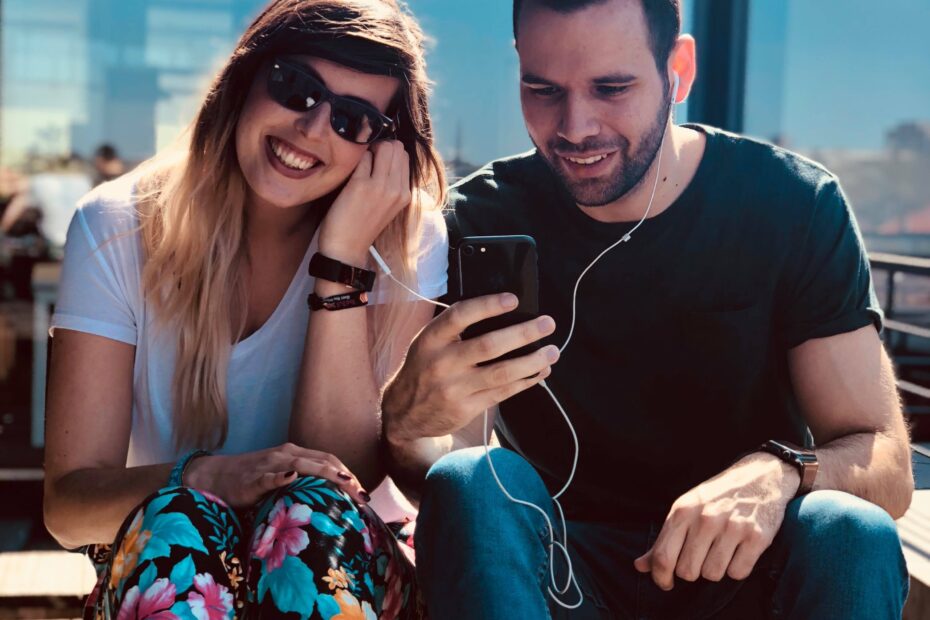 smiling woman and man couple sharing in ear earphones listening to audiobooks.