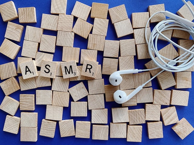 Wood scrabble blocks with ASMR spelled out, white in ear headphones with coiled cord. Used as image for ASMR audiobooks post.