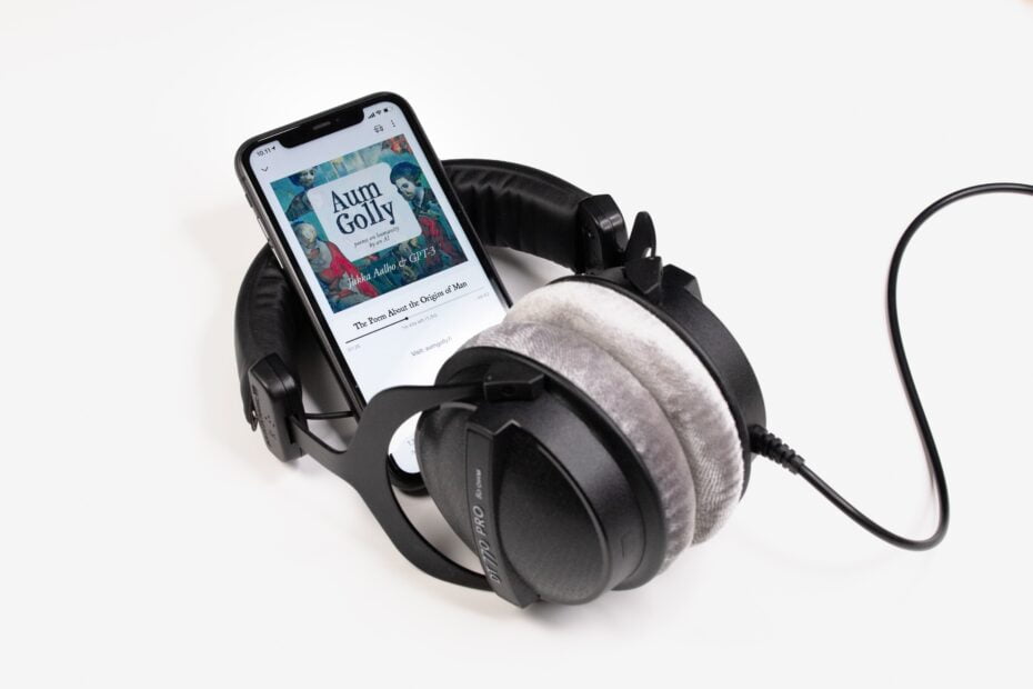 Smartphone playing an audiobook resting on over ear headphones. Used as audiobook image.