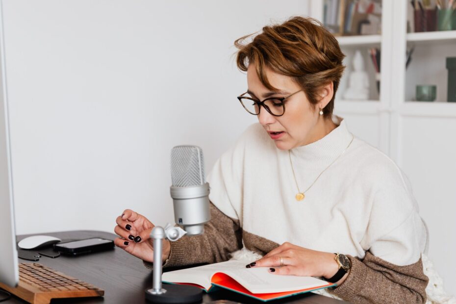 audiobook narrator list - woman reading book for audiobook recording at desk